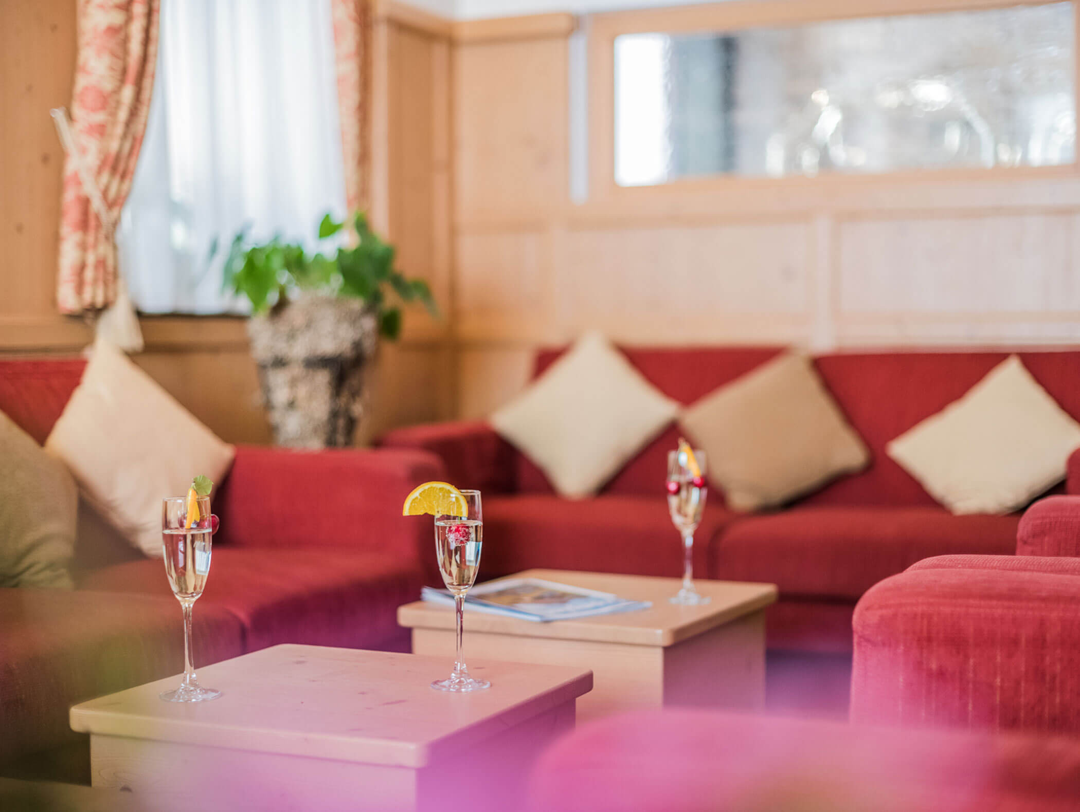 Three glasses of Prosecco on the wooden tables in the lobby - Wirtshaushotel Alpenrose