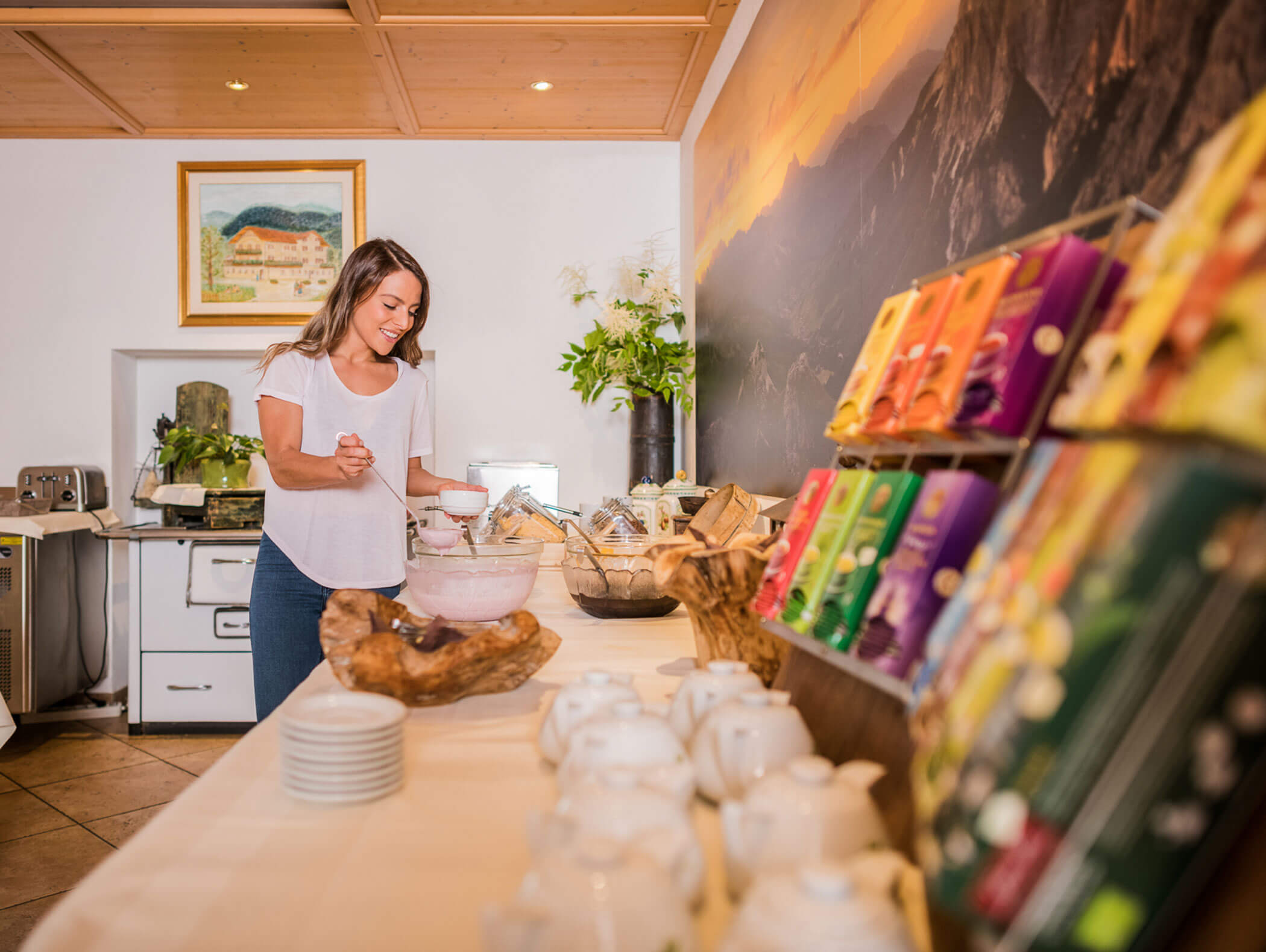 Woman taking yogurt from the bowl, various teas in the foreground - Wirtshaushotel Alpenrose