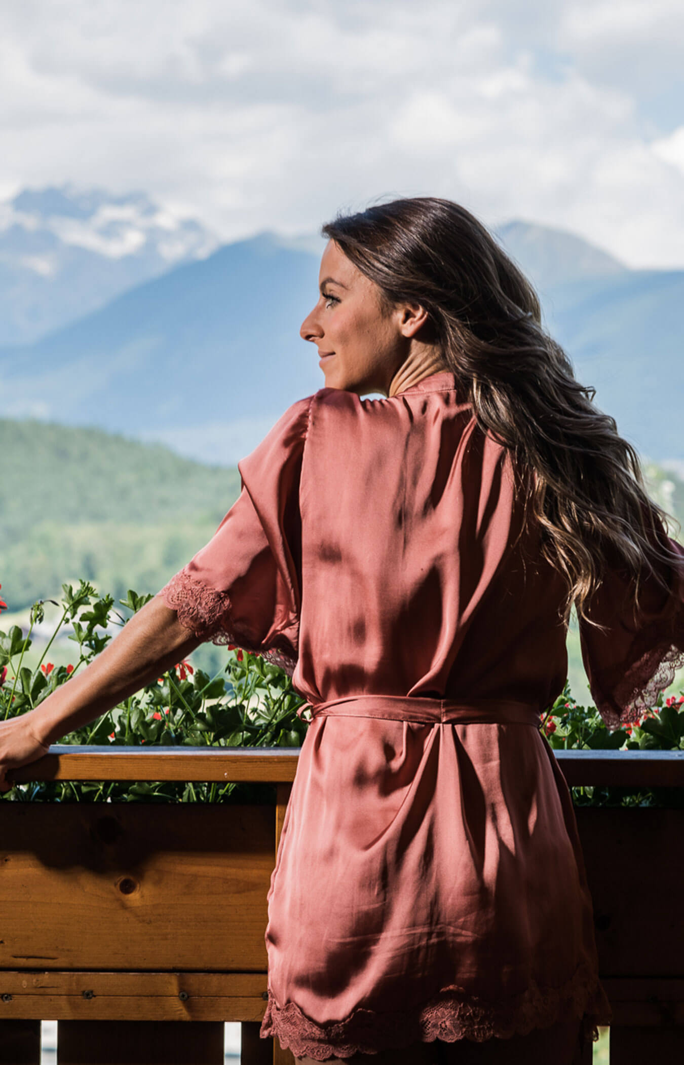 Frau steht im Sommer auf dem Balkon und genießt das Bergpanorama - Wirtshaushotel Alpenrose