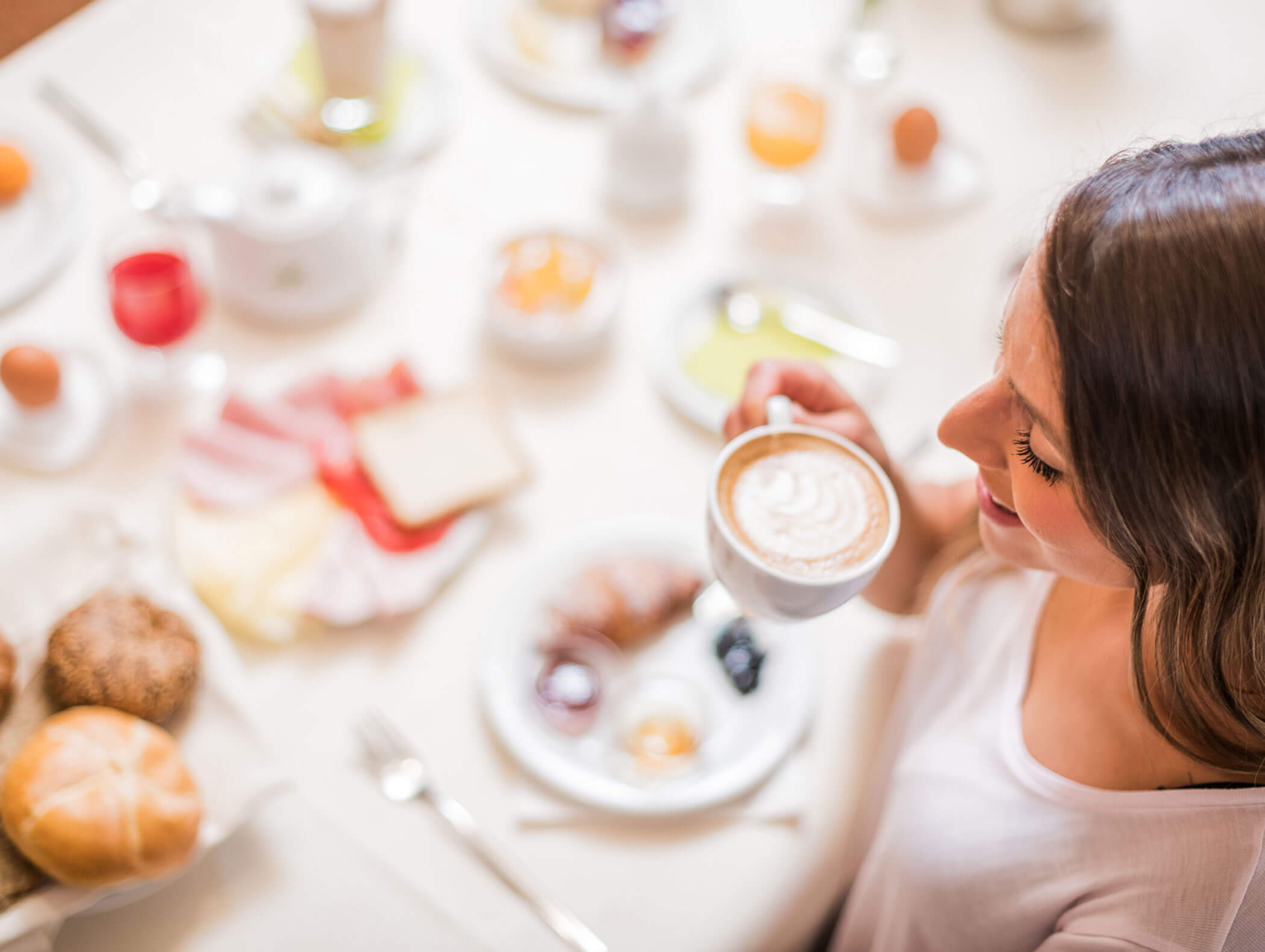 Frau trinkt Cappuccino am Frühstückstisch - Wirtshaushotel Alpenrose