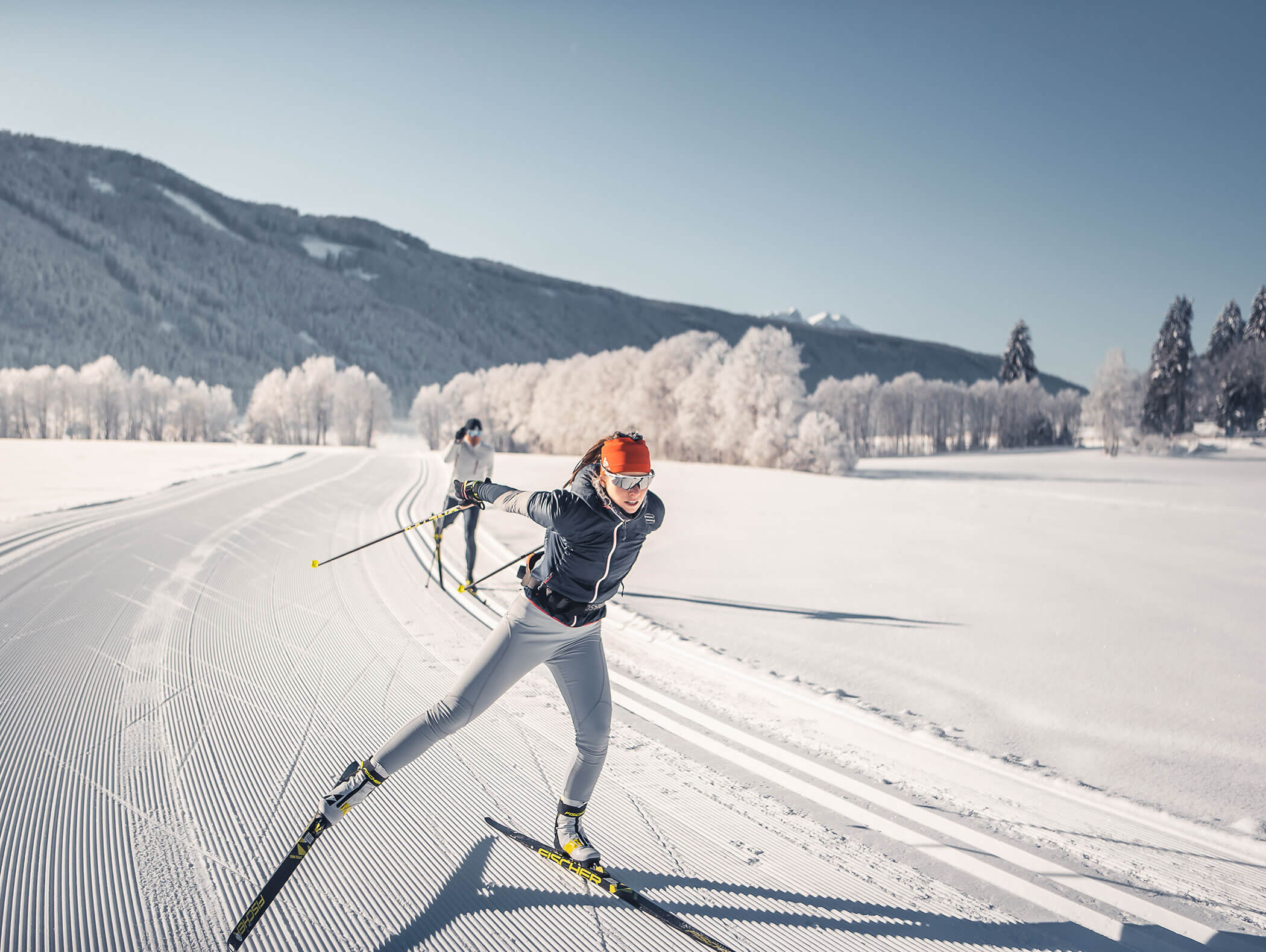 Zwei Langläufer auf der Loipe mit verschneiten Bäumen im Hintergrund - Wirtshaushotel Alpenrose