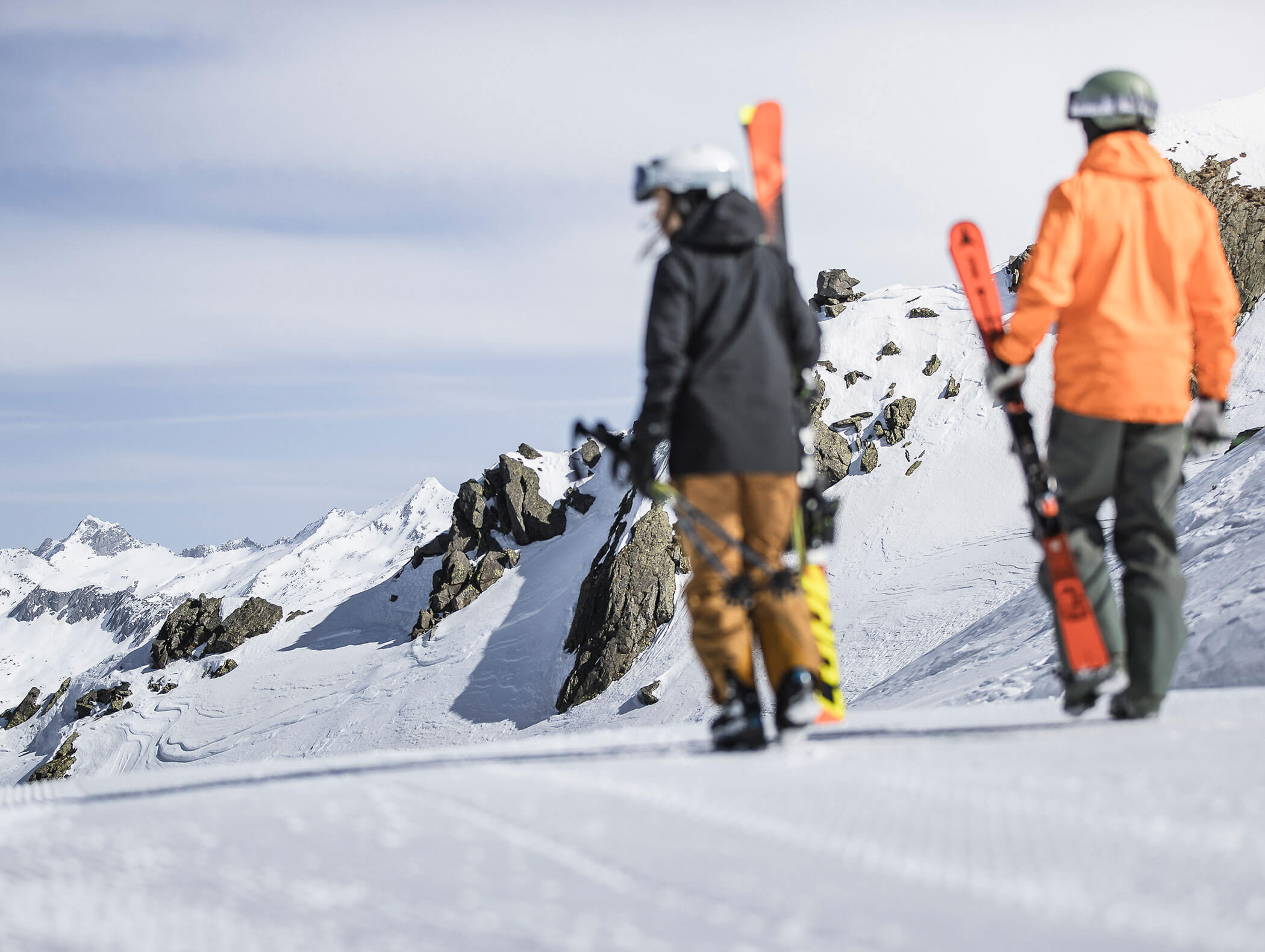 Two skiers walk to the slope of Plan de Corones with mountains and stones in the background - Wirtshaushotel Alpenrose