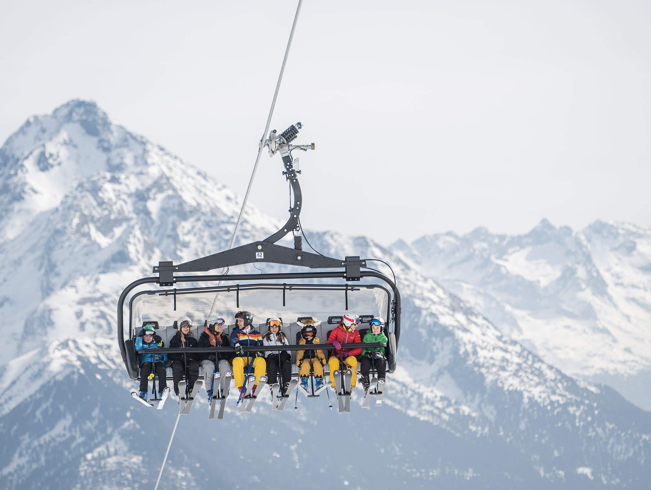 Adults and children on the Plan de Corones chairlift with mountain landscape in the background - Wirtshaushotel Alpenrose